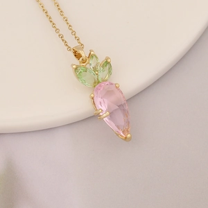 Close-up of carrot pendant necklace with pink teardrop and green crystals on 18k gold chain