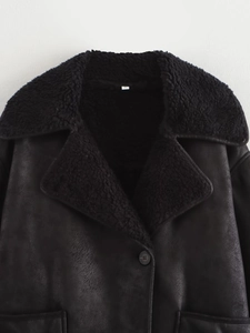 Détail d'un manteau noir en similicuir et peau lainée montrant la texture pelucheuse