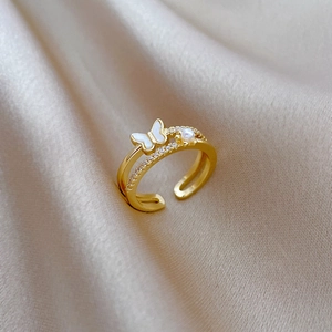 Gros plan d'une bague papillon dorée avec perles et cristaux sur soie de champagne
