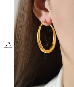 Model wearing large polished gold stainless steel hoop earrings for a luxury look