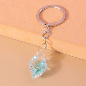 Close-up of a transparent conch keychain with shells inside on a two-tone background