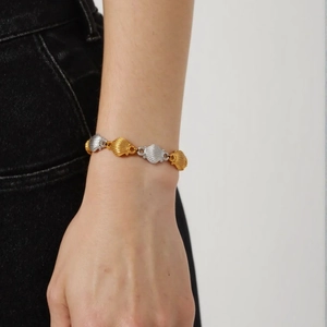 Two-tone gold and silver stainless steel seashell chain bracelet worn on a wrist