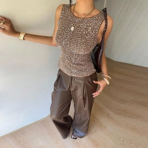 Détail du haut sans manches à paillettes scintillantes et du pantalon en cuir taille haute