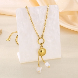 Détail du collier en acier doré avec pendentif en coquille et glands de perles sur plateau