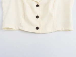 Detail of beige cropped blazer with dark brown tortoiseshell buttons and hemline craftsmanship