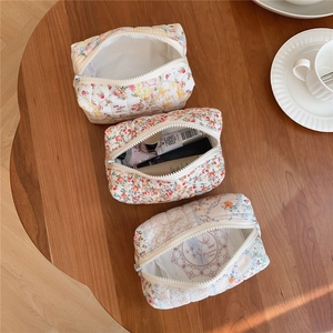 Flat lay of floral quilted cotton makeup bags with skincare products inside on a table