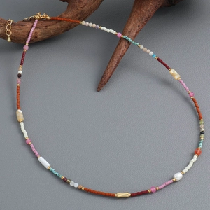 Collier bohème en perles colorées avec pierres naturelles et coquillages sur bois sombre