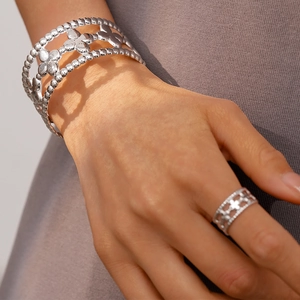 Detailed macro view of silver floral cuff bracelet and matching ring with beaded edges