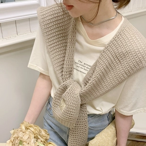 Close-up of beige knitted shawl with hollow mesh design and front knot detail