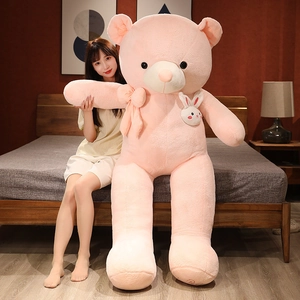 Giant pink teddy bear plush with a bow and rabbit accessory in a home setting