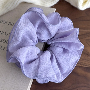 Detailed close-up of a large purple ruffled scrunchie on a book with texture details