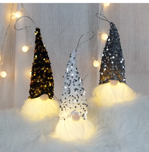 Close-up of three glowing Christmas sequin gnomes with plush beards and LED warm lights