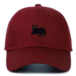 Detailed close-up of a burgundy baseball cap with a black cat embroidery and yellow eyes