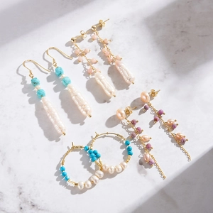 Elegant gold earrings with natural turquoise and baroque pearls on white marble