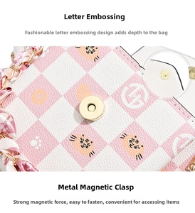 Detail of pink plaid phone bag featuring cartoon cat print and gold magnetic buckle closure