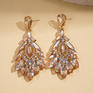 Detail of luxury teardrop drop earrings with champagne crystals and golden metal leaf design