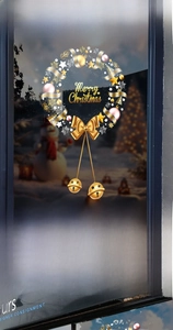 Detail of golden Christmas wreath window sticker with bells and Merry Christmas text