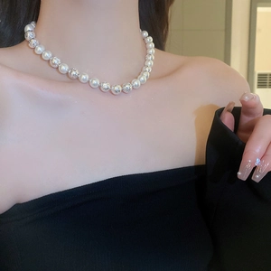 Detail of elegant pearl necklace with hollow silver beads worn on a model's collarbone
