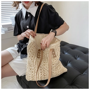 Close-up of woven cutout pattern on beige tote bag with brown leather handles and stitching