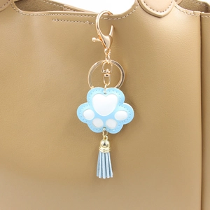 Porte-clés patte de chat en cuir PU avec pompon bleu sur un sac à main beige