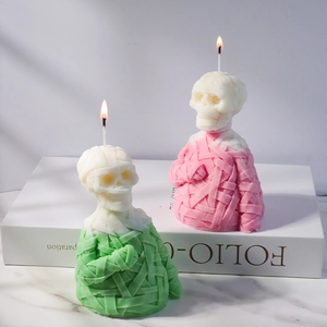 Halloween mummy skull candle in mint green and pink colors with bandage texture on a stand