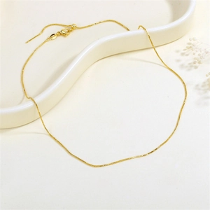 Elegante collana a catena dorata con chiusura a moschettone su un vassoio bianco minimal