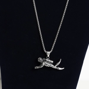 Macro view of a detailed diver pendant with box chain on a black velvet display