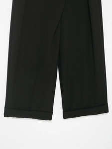 Detailed close-up of the black dress trousers featuring high-quality cuffed hem stitching