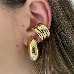 Macro shot of minimalist gold chunky hoop earrings and triple-layered ear cuff set