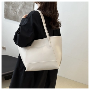 Sac fourre-tout minimaliste en cuir crème porté par un mannequin pour un style quotidien