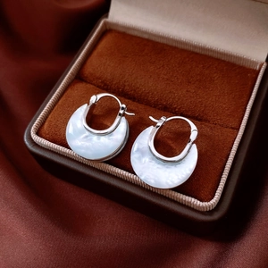 Close-up of silver U-shaped earrings with mother of pearl inlay in a velvet box