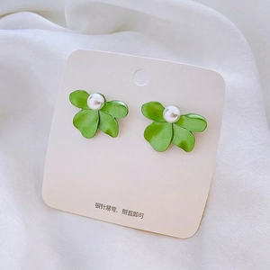 Close-up of green tulip flower earrings with white pearl and 925 silver needle on silk