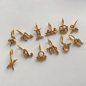 Detalle de 12 colgantes del zodiaco chapados en oro con circonitas sobre un fondo blanco