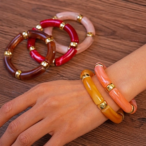 Vue détaillée de bracelets colorés en acrylique style bambou avec perles dorées sur bois