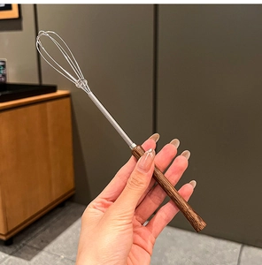 Close-up of mini stainless steel whisk with ergonomic dark wood handle for home baking
