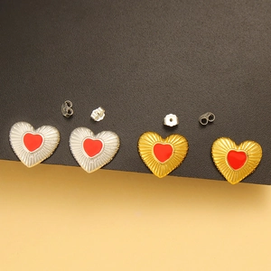 Macro shot of 925 sterling silver heart studs in gold and silver with red enamel