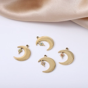 Detailed view of four gold moon and colorful star charms on a soft beige silk background