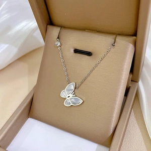 Macro shot of silver butterfly necklace with white mother of pearl in a brown jewelry box