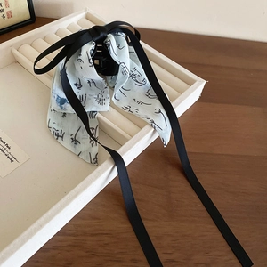Detail of a chic bow hair claw clip featuring ink calligraphy print and satin ribbons