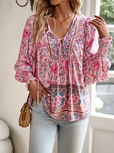 Detail of bohemian floral print blouse with V-neck tie and elastic cuffs in natural light