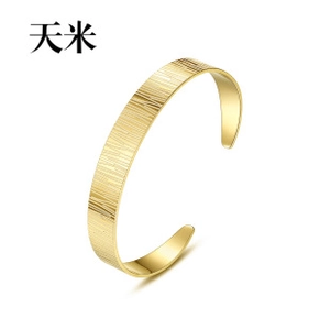 Close-up of golden brushed stainless steel open bangle showing detailed metal texture
