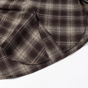 Gros plan d'une chemise à carreaux marron vintage avec ourlet à double couture et coton tissé