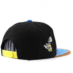 Detail of black snapback hat showing yellow adjustable strap and cartoon embroidery