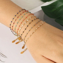 Detail of colorful enamel bead bracelets on gold stainless steel chain worn on wrist