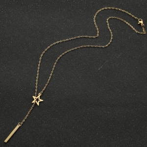Detailed view of the 18K gold star and bar pendant Y-necklace on a textured black surface