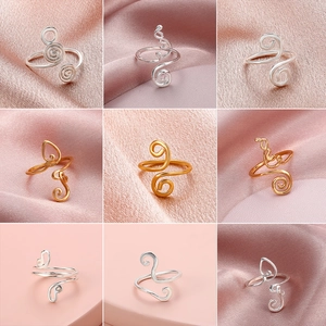 9-piece set of gold and silver wire-wrapped adjustable rings on pink silk background