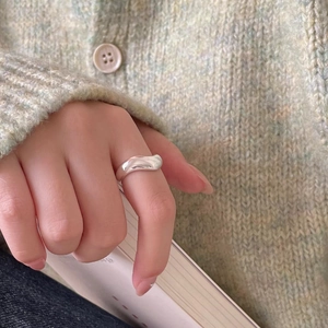 Close-up of minimalist 925 sterling silver curved wave ring worn on model hand