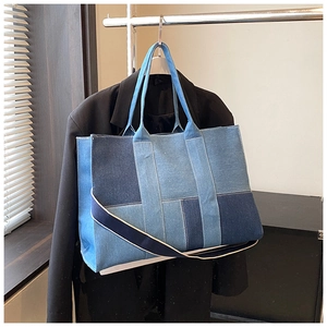 Detail of denim patchwork tote bag with contrast stitching and adjustable shoulder strap