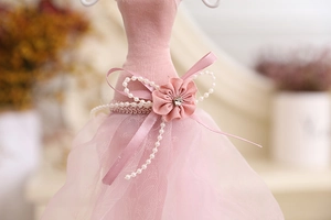 Detail of pink mannequin jewelry stand with satin fabric, lace skirt and pearl accents