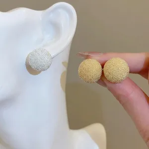 Textured round stud earrings in gold and silver finishes worn by a female model
